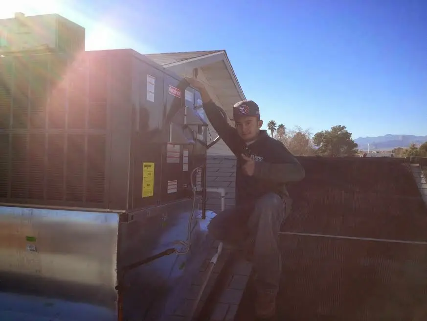 HVAC technician performing AC Tune-Up on a rooftop unit in Lyons